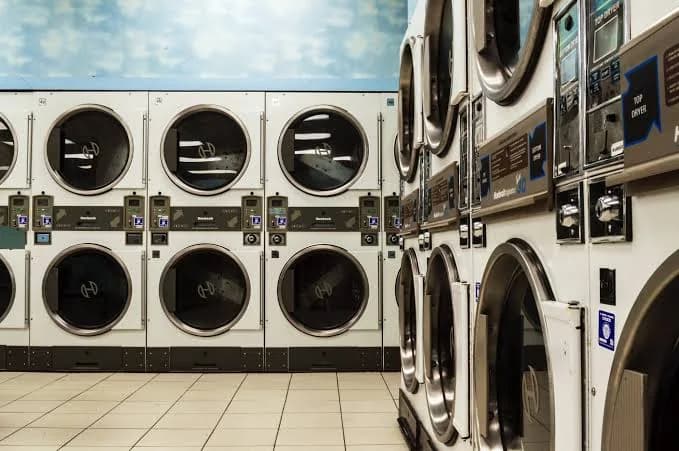 Rows of coin-operated commercial washers and dryers in a laundromat