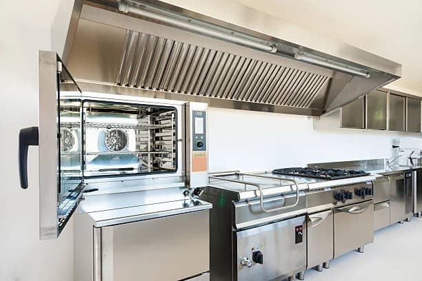 Commercial oven and range line under a kitchen hood